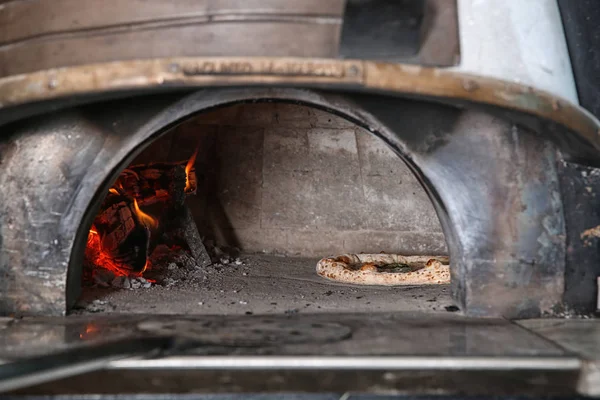 Brinnande ved och välsmakande pizza i ugnen på restaurang kök — Stockfoto