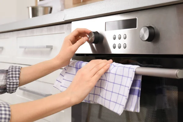 Junge Frau stellt Backofen in Küche ein, Nahaufnahme — Stockfoto