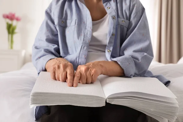 Blind senior persoon lezen boek geschreven in braille op bed binnenshuis, close-up — Stockfoto