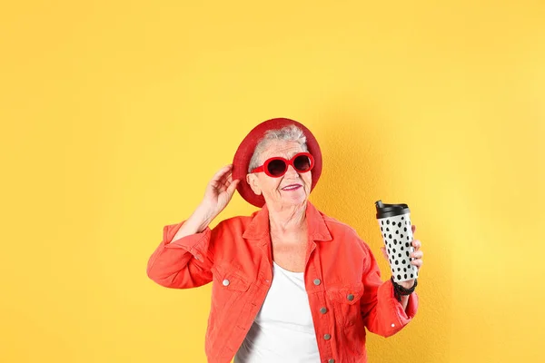 Портрет крутої бабусі з напоєм на кольоровому фоні — стокове фото