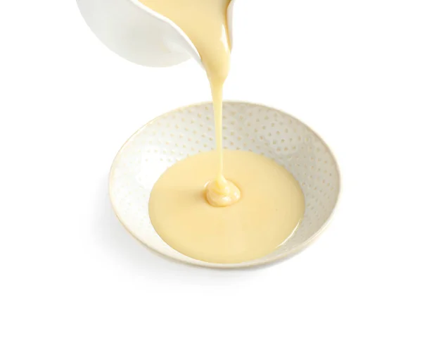 Pouring condensed milk from jug into bowl on white background. Dairy product — Stock Photo, Image