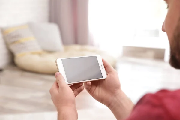 Hombre joven que utiliza el chat de vídeo en el teléfono inteligente en casa, primer plano. Espacio para el diseño — Foto de Stock