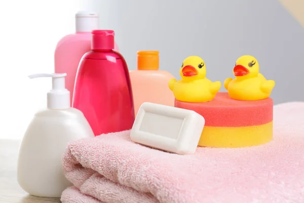 Dětské kosmetické prostředky, hračky a ručník proti barevnému pozadí, zaostřená — Stock fotografie