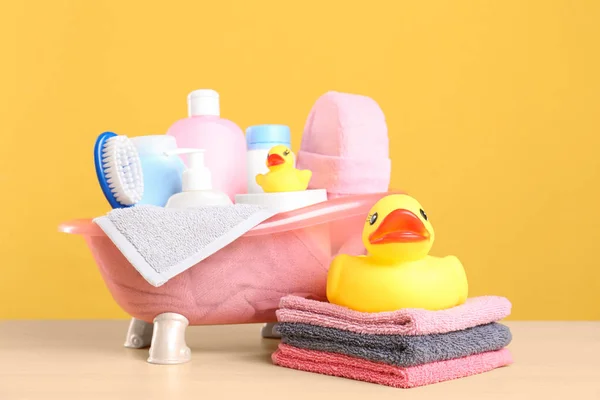 Baby cosmetic products, toys and towels on table against color background — Stock Photo, Image