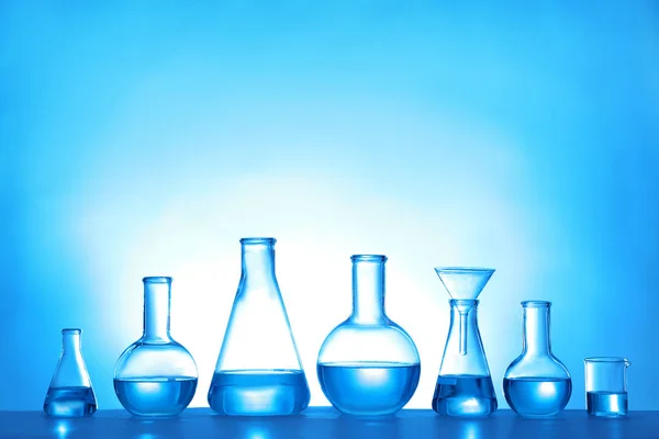Vidros de laboratório com líquido sobre fundo de cor. Química da solução — Fotografia de Stock