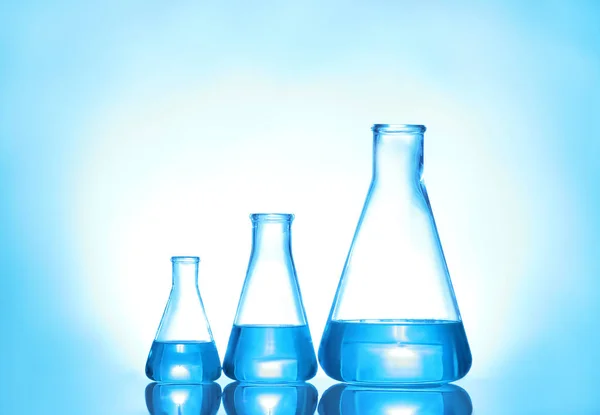 Vidros de laboratório com líquido sobre fundo de cor. Química da solução — Fotografia de Stock