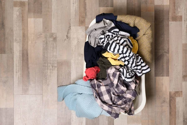 Laundry basket with dirty clothes on floor, top view. Space for text