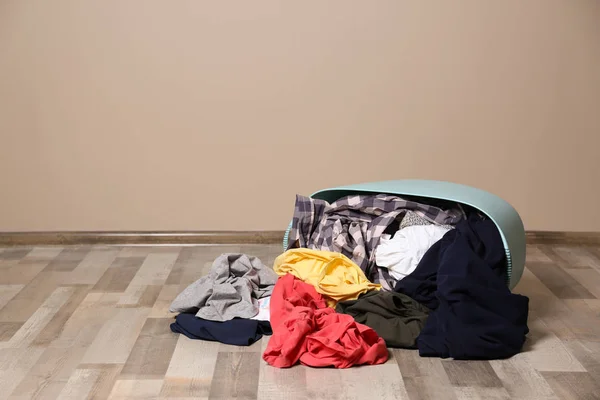 Vuile kleren verspreid van wasmand op de vloer binnenshuis. Ruimte voor tekst — Stockfoto