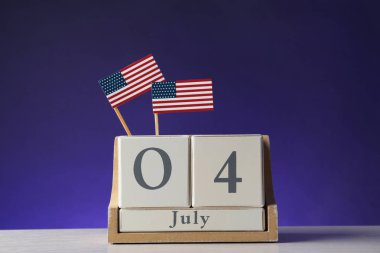 Masanın üzerinde Usa bayrakları olan ahşap takvim renk arkaplanına karşı. Bağımsızlık Gününüz kutlu olsun.