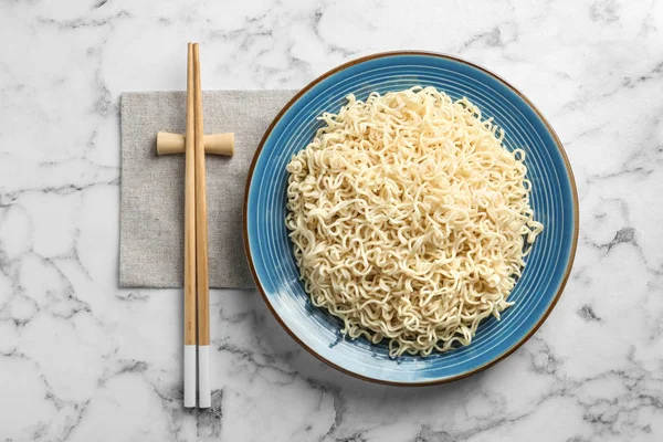 Prato de macarrão saboroso e pauzinhos servidos em mesa de mármore, flat lay — Fotografia de Stock