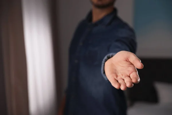 Man offering helping hand on blurred background, closeup. Space for text — Stock Photo, Image