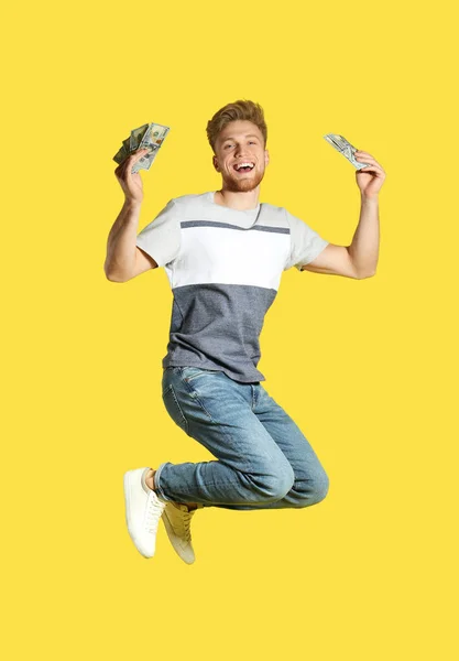 Joven saltando con dinero en el fondo de color — Foto de Stock