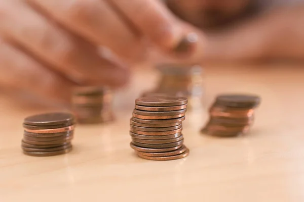 Montón de monedas y hombre borroso en la mesa, primer plano. Contando dinero — Foto de Stock