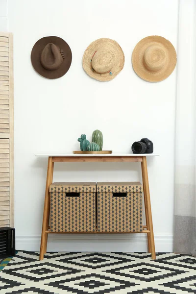 Stylish wooden table with boxes at white wall in room — Stock Photo, Image