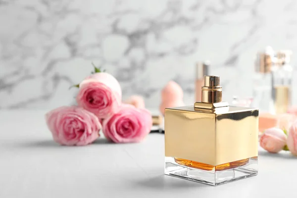 Fles parfum en rozen op tafel tegen marmeren achtergrond. Ruimte voor tekst — Stockfoto