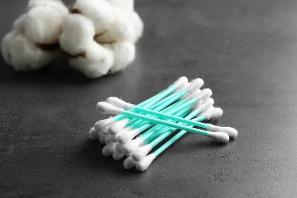 Pile of cotton swabs and flowers on grey table