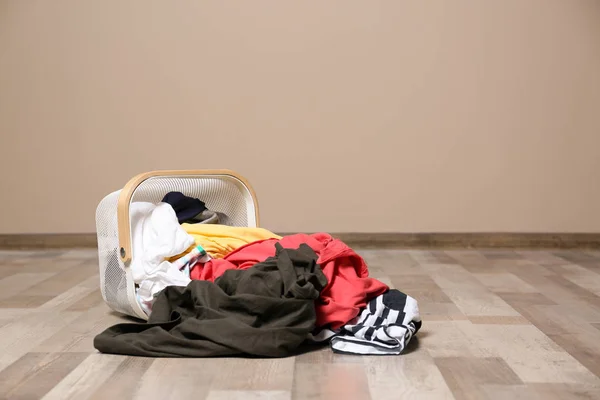 Vuile kleren verspreid van wasmand op de vloer binnenshuis. Ruimte voor tekst — Stockfoto