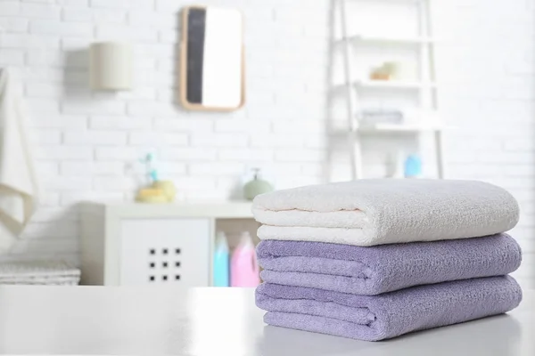 Pila di asciugamani freschi sul tavolo in bagno. Spazio per testo — Foto Stock
