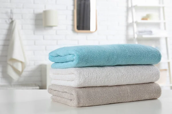 Stack of fresh towels on table in bathroom, closeup — Stock Photo, Image