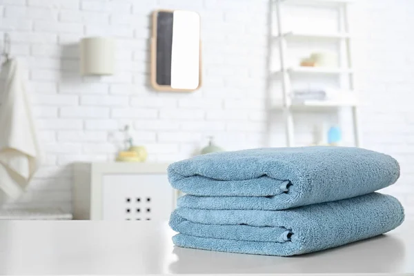 Pila di asciugamani freschi sul tavolo in bagno. Spazio per testo — Foto Stock