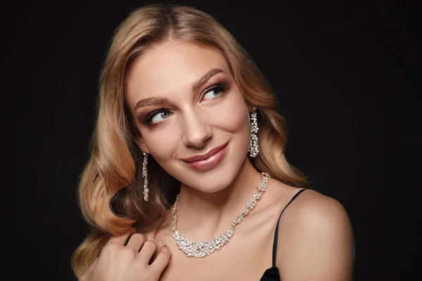 Belle jeune femme avec des bijoux élégants sur fond sombre — Photo