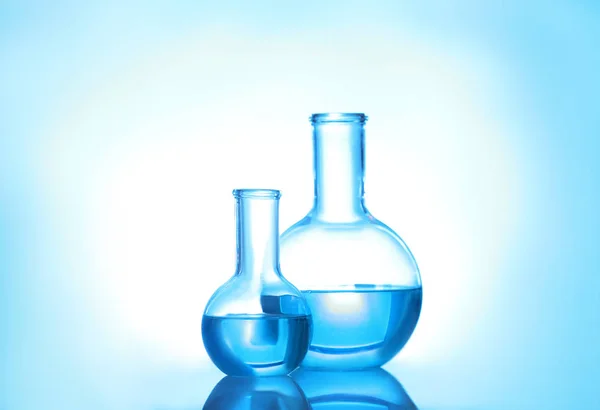 Laboratory glassware with liquid on color background. Solution chemistry Royalty Free Stock Photos