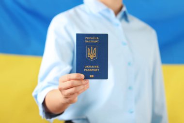 Ukrayna pasaportu taşıyan kadın ulusal bayrağa karşı, yakın plan. Uluslararası ilişkiler