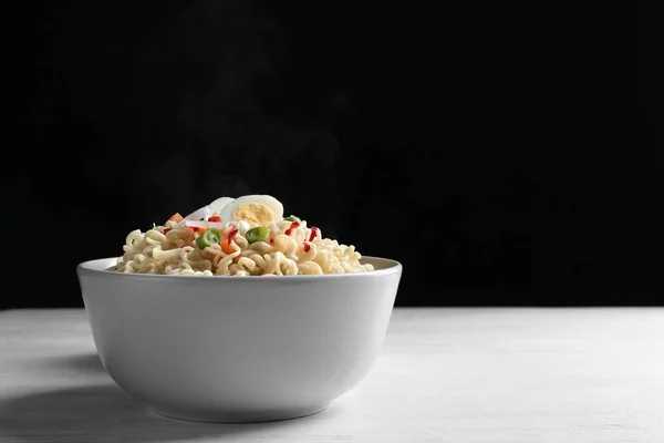 Tigela de macarrão quente com ovo e legumes na mesa contra fundo preto. Espaço para texto — Fotografia de Stock