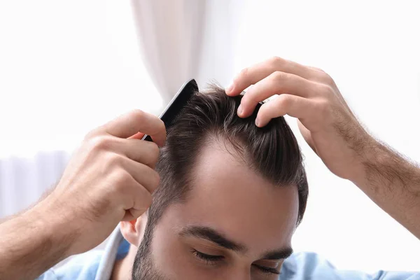 Young man with comb indoors, closeup. Hair loss problem — 스톡 사진