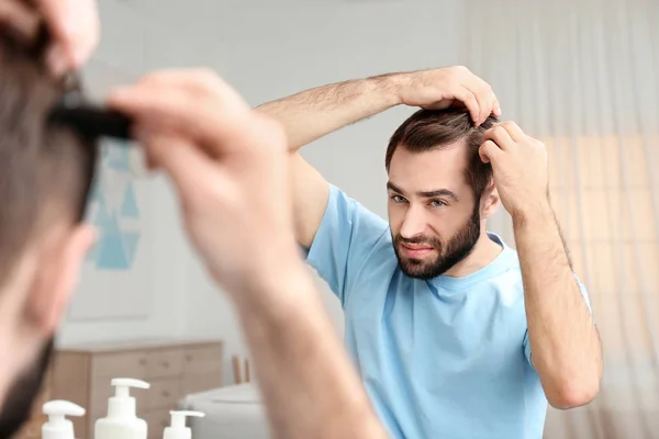 Young man with hair loss problem in front of mirror indoors — Stock Photo, Image