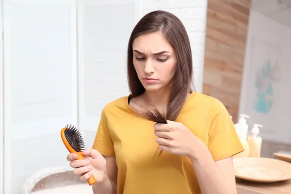 Mujer joven con cepillo en el interior. Problema de pérdida de cabello — Foto de Stock