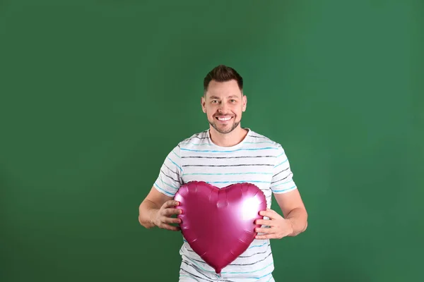 Retrato de hombre joven con globo en forma de corazón sobre fondo de color — Foto de Stock