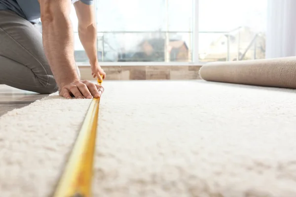 Man measuring carpet indoors. Construction tool — Stock Photo, Image