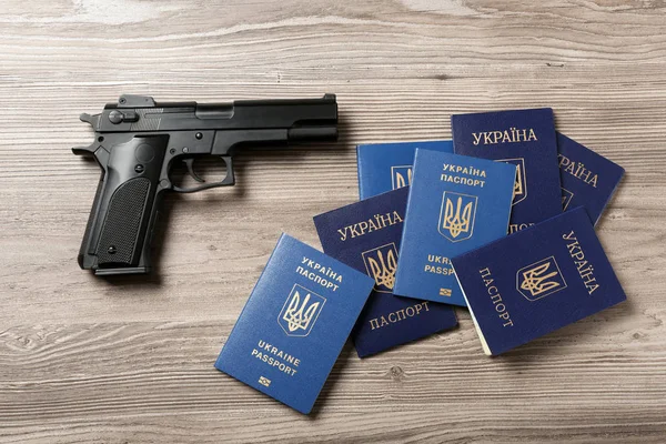 Пистолет с украинскими паспортами на деревянном фоне, квартира лежала — стоковое фото