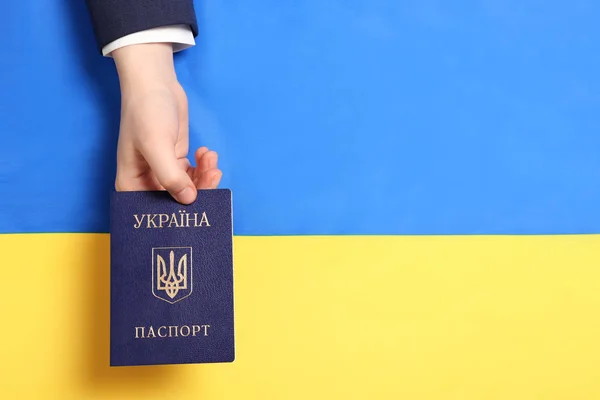 Женщина с украинским внутренним паспортом над национальным флагом, вид сверху. Пространство для текста — стоковое фото