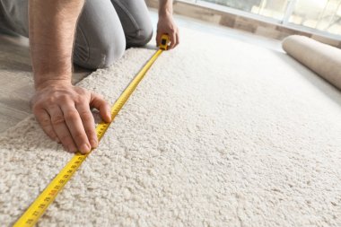 İçeride halı ölçen adam, yakın çekim görünümü. İnşaat aleti