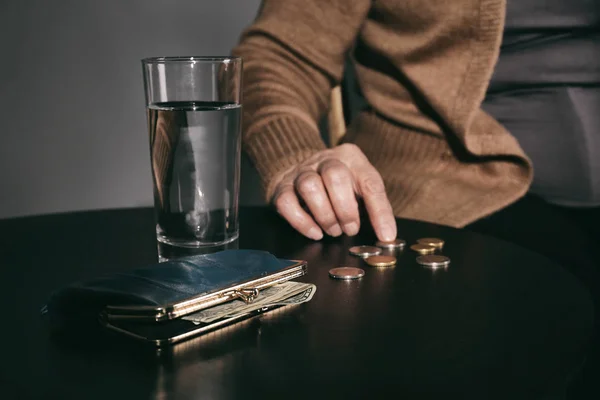 Pobre anciana con agua, billetera y monedas en la mesa, primer plano — Foto de Stock