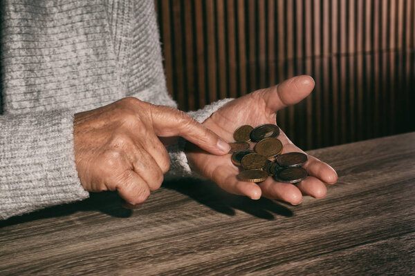 Poor senior woman with coins at table, closeup
