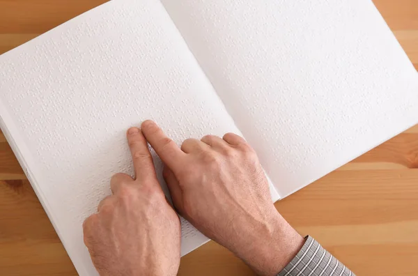 Сліпий людина читання книги, написаної на Braille в таблиці, вид зверху — стокове фото