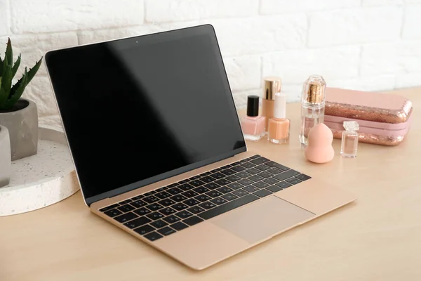 Local de trabalho elegante com laptop moderno e produtos cosméticos na mesa perto da parede de tijolo. Blogueiro de beleza — Fotografia de Stock