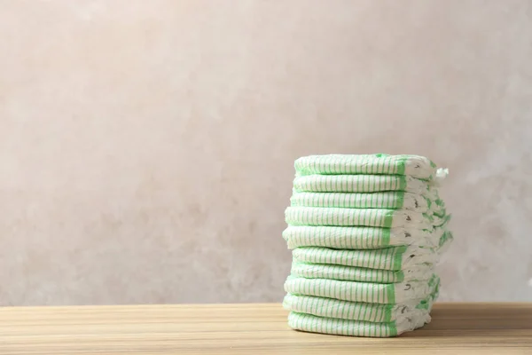 Stack of diapers on table against color background, space for text. Baby accessories — Stock Photo, Image