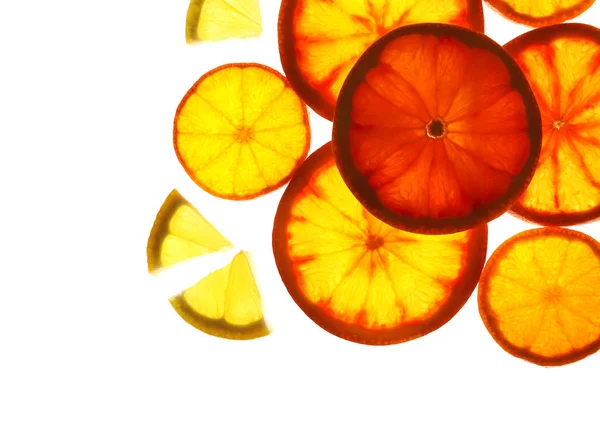 Illuminated slices of citrus fruits on white background, top view — Stock Photo, Image