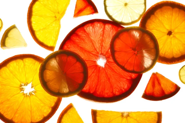 Illuminated slices of citrus fruits on white background, top view — Stock Photo, Image