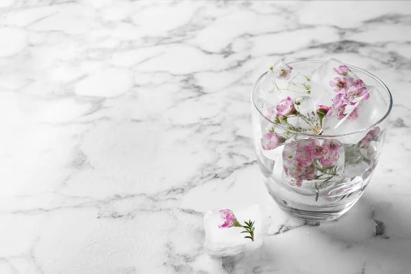 Copo de água com cubos de gelo florais na mesa. Espaço para texto — Fotografia de Stock