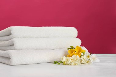 Renk arka plan karşı masada güzel çiçekler ile yumuşak temiz havlu Yığını. Metin için alan