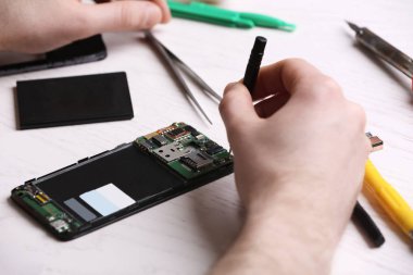 Teknisyen masada cep telefonu tamir, closeup. Cihaz onarım hizmeti