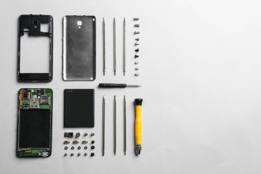 Beyaz arka planda sökülen cep telefonu ve onarım araçları, üst görünüm