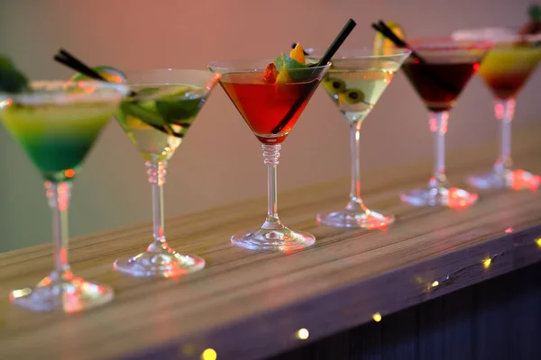 Различные коктейли мартини на столе на размытом фоне — стоковое фото