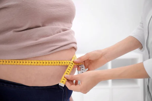 Doctor measuring waist of overweight woman in clinic, closeup — Stock Photo, Image