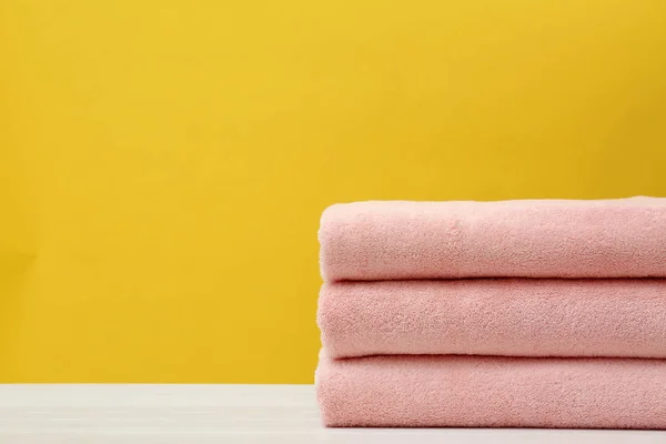 Montón de toallas limpias suaves en la mesa contra el fondo de color. Espacio para texto — Foto de Stock